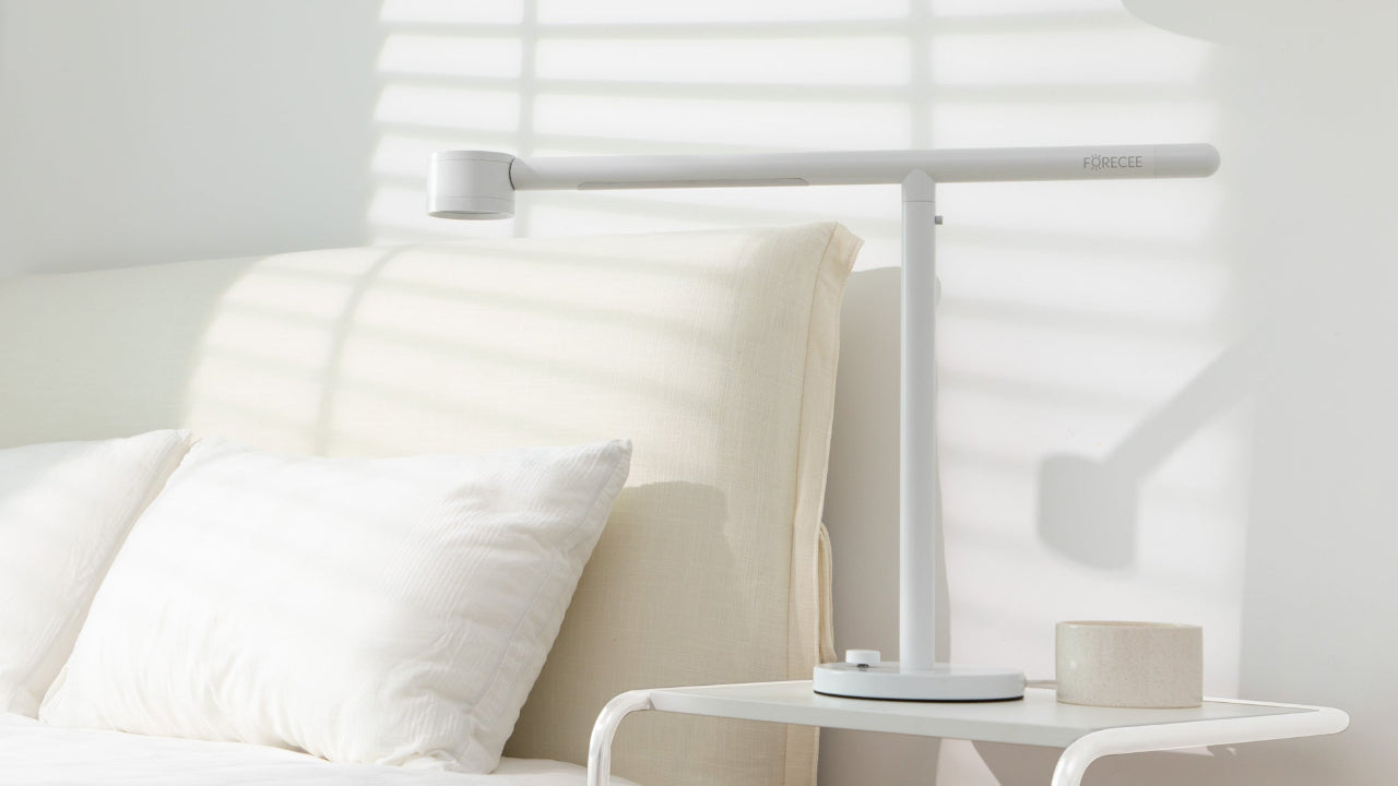 White Forecee Beauty Lamp placed on a bedside table in a well-lit modern bedroom, complementing the cozy, elegant interior.