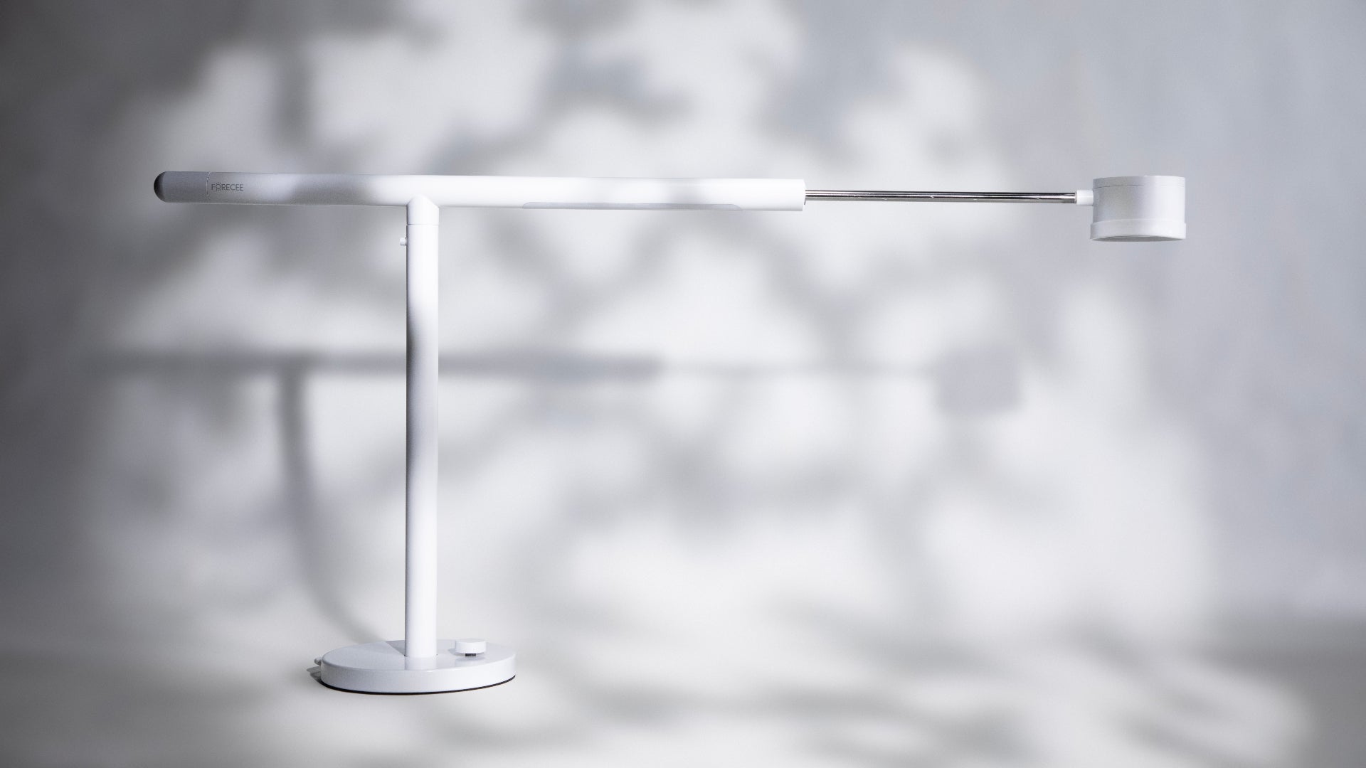 Modern white Forecee Beauty Lamp with extended red lamp casting shadows on a light gray background