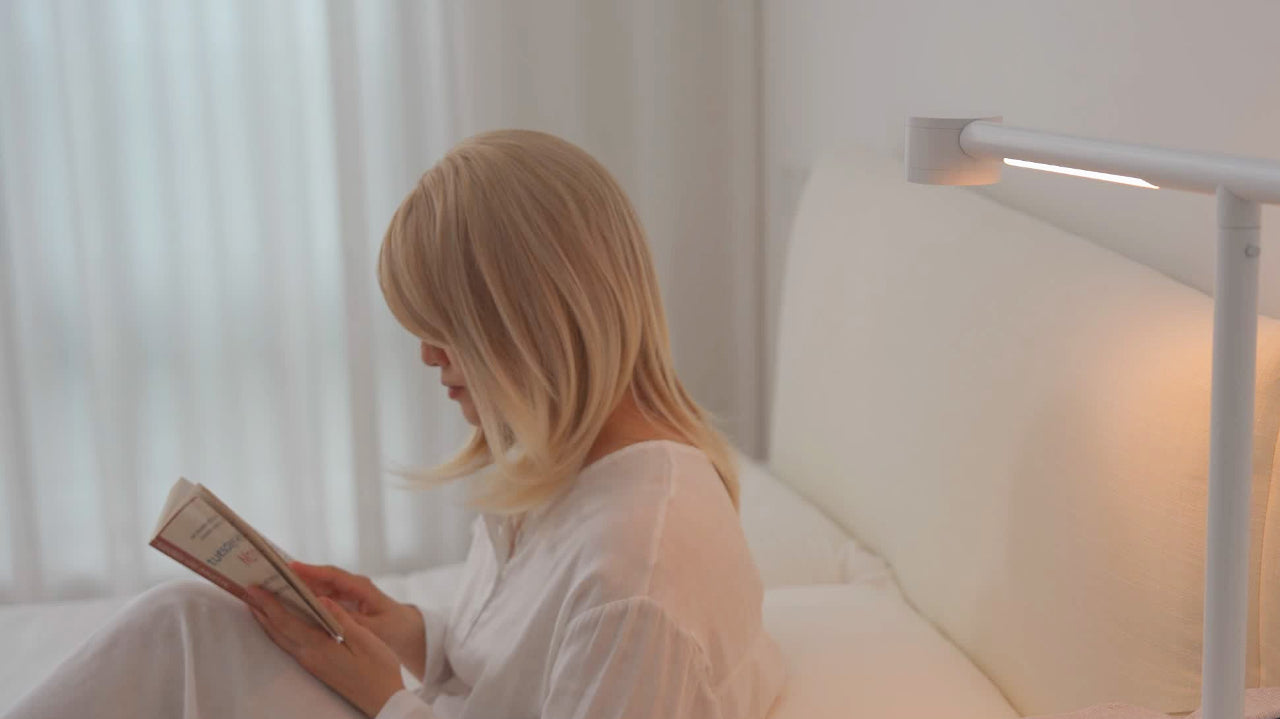 Forecee Beauty Lamp in reading mode illuminating a woman reading a book in a softly lit room.
