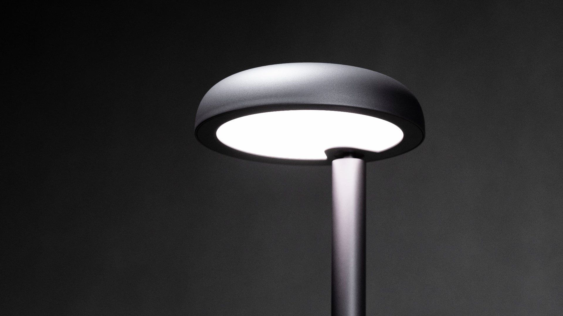 Modern Forecee desk lamp on a dark background, lamp is turned on showing uniform illumination
