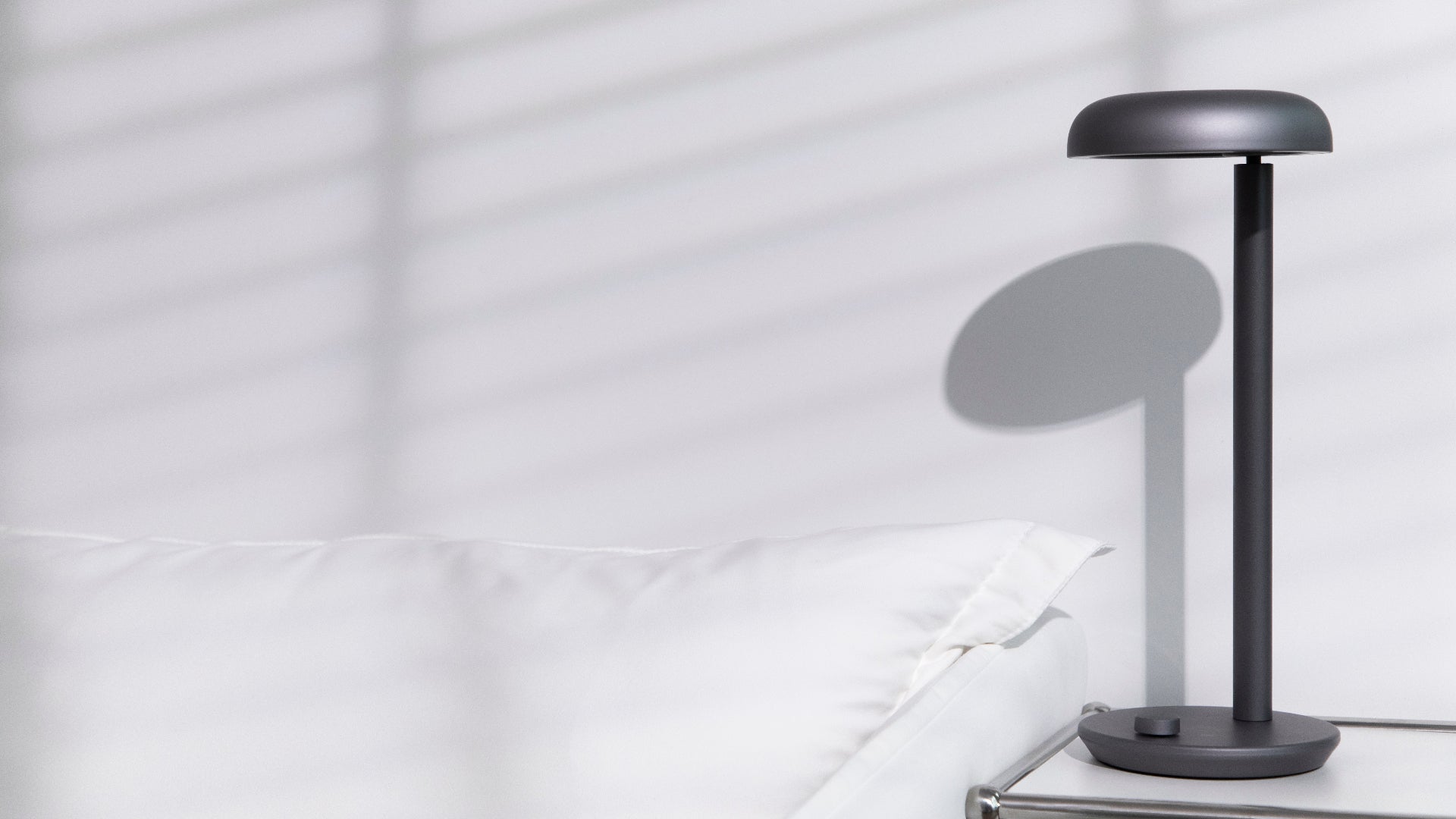 Grey Forecee Desk Lamp placed on a minimalist white nightstand, fitting seamlessly into modern home decor.