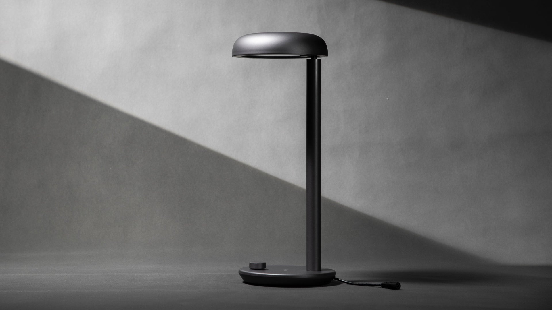 Modern Forecee desk lamp on a light gray background, side view