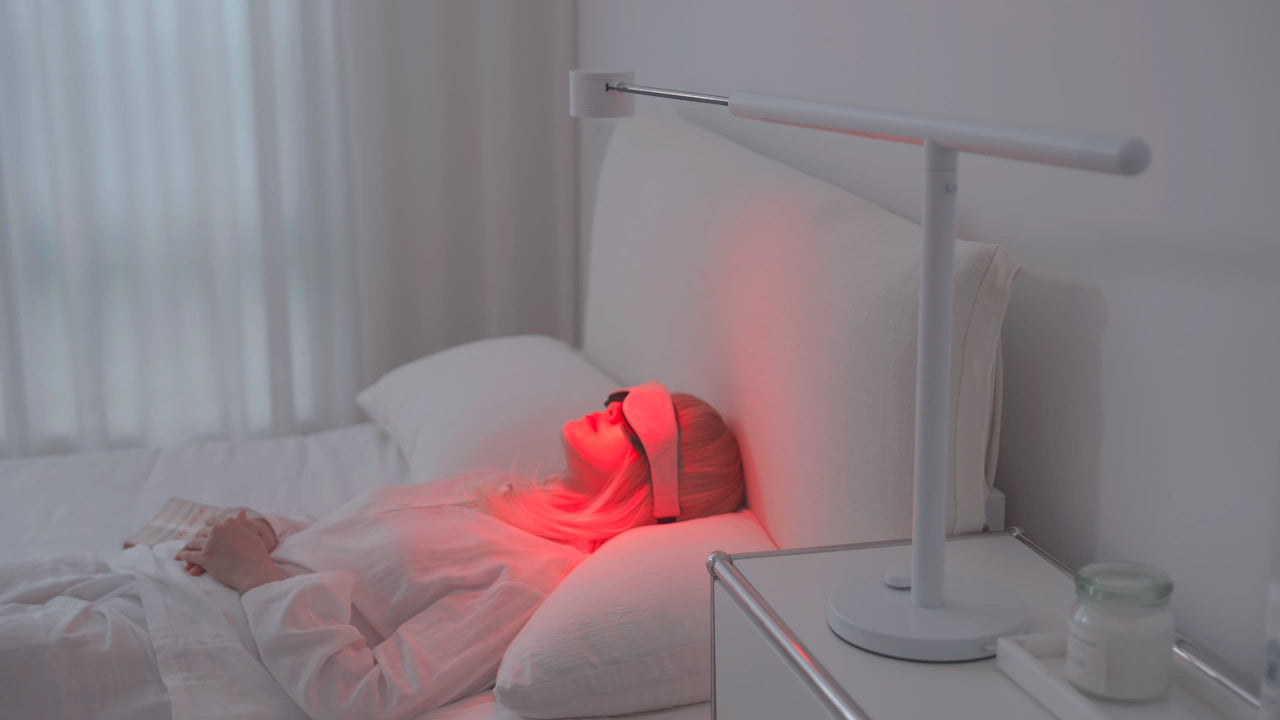 Person lying in bed wearing an eye mask beside a Forecee Beauty Lamp emitting red light during a red-light-therapy session.